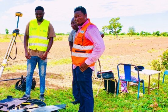 Burkina Faso Flying Labs team wearing reflector vests and setting up a drone outside to conduct a topographic survey.