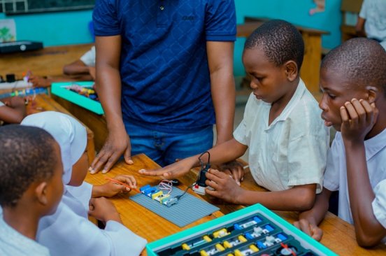 Young students in uniform concentrate as an instructor from Tanzania Flying Labs guides them on how to use a World Science Movement STEM kit.