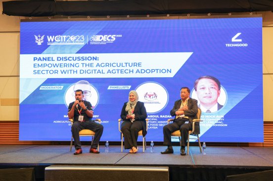 The three panelists at the 'Empowering the Agriculture Sector with Digital AgTech Adoption' discussion sitting on stage in front of a screen with the panel information.