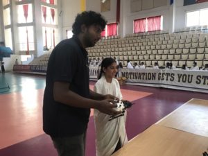 A man and child holding drone wireless controllers in an auditorium.