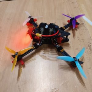 A colorful quadracopter drone sitting on a table top