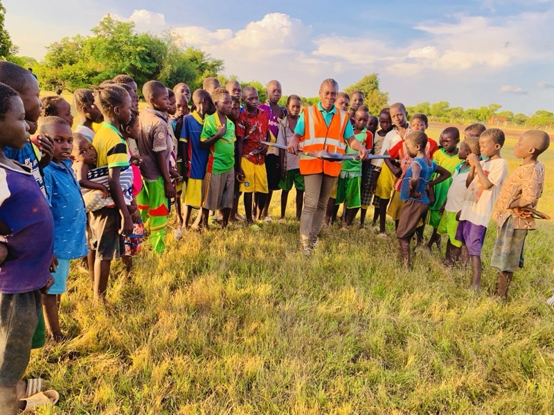 Group of young students and an instructor holding a fixed-wing drone in a field